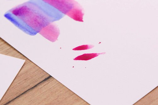 Dos impresiones a pincel de color rosa y salpicaduras sobre papel de acuarela.